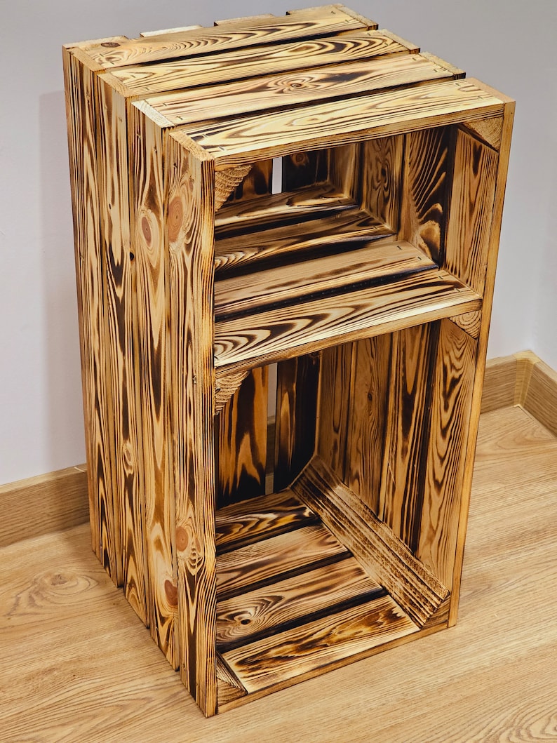 May include: A wooden shelf unit made from reclaimed wood with a rustic, burnt finish. The shelf has two open shelves and is ideal for displaying decorative items or storing small items.