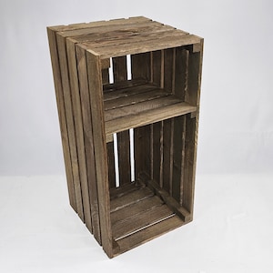 May include: A rustic wooden crate shelf with two shelves. The crate is made of dark brown wood and has a distressed finish.