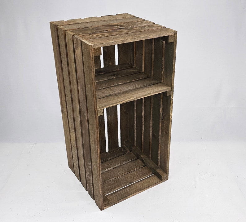 May include: A rustic wooden crate shelf with two shelves. The crate is made of dark brown wood and has a distressed finish.