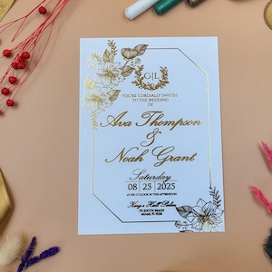 Elegante invitación de boda floral dorada con escritura en relieve y marco delicado: diseño botánico de lujo para bodas formales.