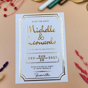 Tarjeta de invitación para guardar la fecha con relieve dorado clásico: diseño de escritura y calendario con marco elegante, cartulina blanca para anuncio de boda.