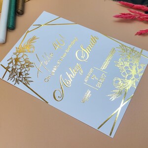 Elegante invitación de boda en relieve dorado con monograma personalizado y detalle de bambú: diseño clásico y lujoso.