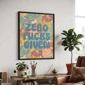 May include: A framed art print with the text "ZERO FUCKS GIVEN" in blue bubble letters. The background features a colorful floral pattern in shades of orange, green, and yellow. The artwork is displayed in a living room setting.