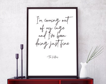 May include: Black framed print with white background and black text that reads "I'm coming out of my cage and I've been doing just fine - The Killers". The print is on a red shelf with black trim and black legs. There are books, a clock, and a toy car on the shelf.
