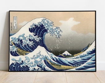 May include: Framed print of Hokusai's "The Great Wave off Kanagawa." The artwork depicts a large ocean wave with white foam cresting over small boats. The background features a mountain and a light-colored sky. The print is in a black frame.