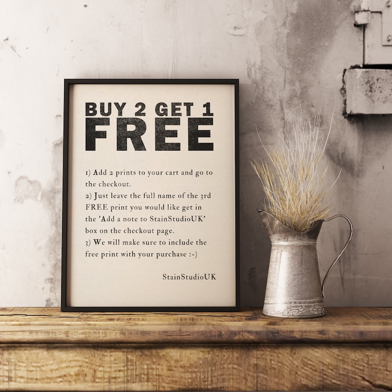 May include: A black and white printable sign with the text "BUY 2 GET 1 FREE" and instructions on how to redeem the offer. The sign is framed and sitting on a wooden surface with a small metal pitcher and dried flowers.