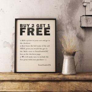 May include: A black and white printable sign with the text "BUY 2 GET 1 FREE" and instructions on how to redeem the offer. The sign is framed and sitting on a wooden surface with a small metal jug and dried flowers.