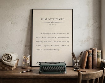 May include: A framed print of "Charlotte's Web" by E.B. White, with a quote from the book. A vintage teal typewriter sits on a wooden desk, along with books, a pen, and a glass cloche with dried flowers.