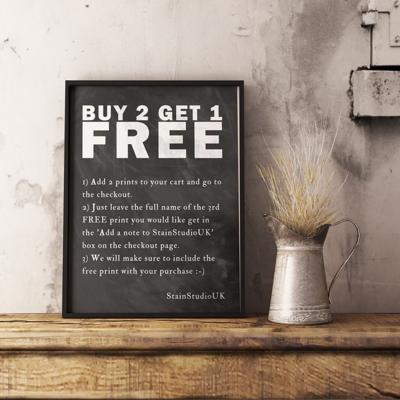 May include: Black and white chalkboard sign with the text "BUY 2 GET 1 FREE" and instructions on how to get a free print. The sign is framed in black and is sitting on a wooden surface.