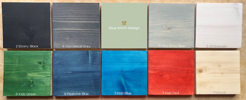 May include: Ten wood samples stained in different colors, including ebony black, gun metal gray, sky gray blue, whitewash, kidz green, peacock blue, kidz blue, kidz red, and natural. The text "YIT blue birch design" is printed on a light green sample.