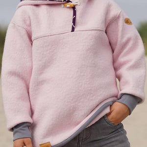May include: A light pink hooded sweatshirt with a toggle closure and a purple anchor pattern inside the hood. The cuffs and hem are gray. A small brown tag is sewn on the lower left side.