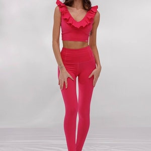 Op de afbeelding: Een roze sportbeha met een gerimpelde halslijn en bijpassende roze leggings. De leggings hebben een hoge taille en een voetloos ontwerp.
