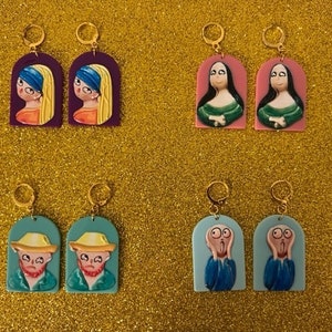 Könnte beinhalten: Ein Set mit sechs Paar Ohrringen, die berühmte Gemälde zeigen. Die Ohrringe sind aus goldfarbenem Metall gefertigt und haben eine rechteckige Form. Die Gemälde umfassen die Mona Lisa, Der Schrei und Mädchen mit Perlenohrring.