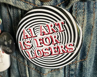 Op de afbeelding: Een zwart-witte knop met een draaiend patroon. De knop heeft rode tekst die "AI Art Is For Losers" luidt.