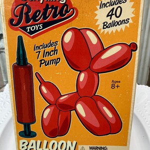 May include: A vintage-style box for a balloon modeling kit. The box is orange with red and white text that reads "Schylling Retro Toys." It includes a 7-inch pump and 40 balloons. A red balloon dog illustration is featured. The kit is for ages 8+.
