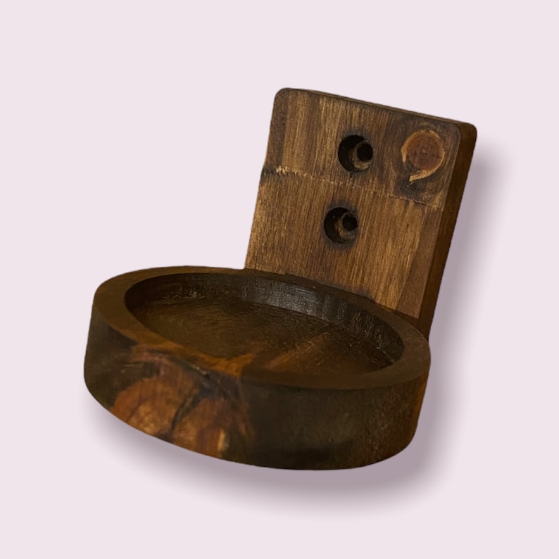 Pu&ograve; includere: Un supporto a parete in legno marrone scuro con un ripiano circolare. Il ripiano ha un bordo liscio e arrotondato e una finitura leggermente pi&ugrave; scura rispetto al supporto a parete.