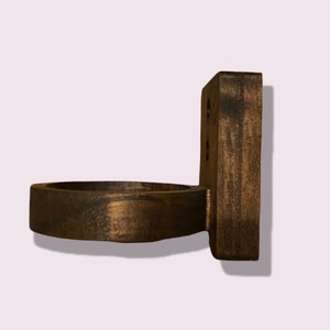 Pu&ograve; includere: Un porta tazze da parete in legno marrone scuro con un'apertura circolare. Il porta tazze ha una finitura rustica ed &egrave; progettato per contenere una tazza o un mug.