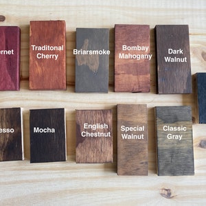 May include: A wood stain color chart with 14 different wood stain colors. The colors are labeled with names like Cabernet, Traditional Cherry, Briarsmoke, Bombay Mahogany, Dark Walnut, Espresso, Mocha, English Chestnut, Special Walnut, Classic Gray, and Ebony.