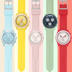 Pu&ograve; includere: Cinque orologi da polso con cinturini di diversi colori. I cinturini sono blu chiaro, giallo, rosa, verde e rosso. Ogni orologio ha un quadrante bianco con segni neri e un cronografo.