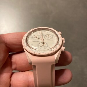 Pu&ograve; includere: Un orologio Omega Speedmaster rosa con quadrante bianco e cinturino in silicone rosa.