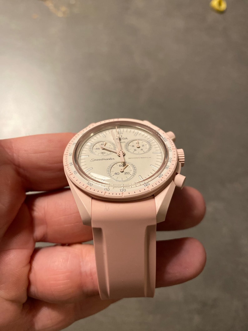 Pu&ograve; includere: Un orologio Omega Speedmaster rosa con quadrante bianco e cinturino in silicone rosa.