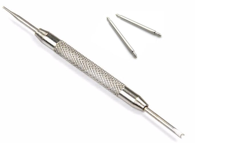 Pu&ograve; includere: Uno strumento per cinturini di orologio argentato con un'impugnatura testurizzata e due barre a molla. Lo strumento viene utilizzato per rimuovere e installare i cinturini degli orologi.