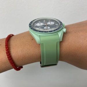 Pu&ograve; includere: Un orologio da polso verde con quadrante nero e lancette argentate. L'orologio ha una funzione cronografo e una scala tachimetrica sulla lunetta. L'orologio &egrave; su un cinturino in gomma verde.