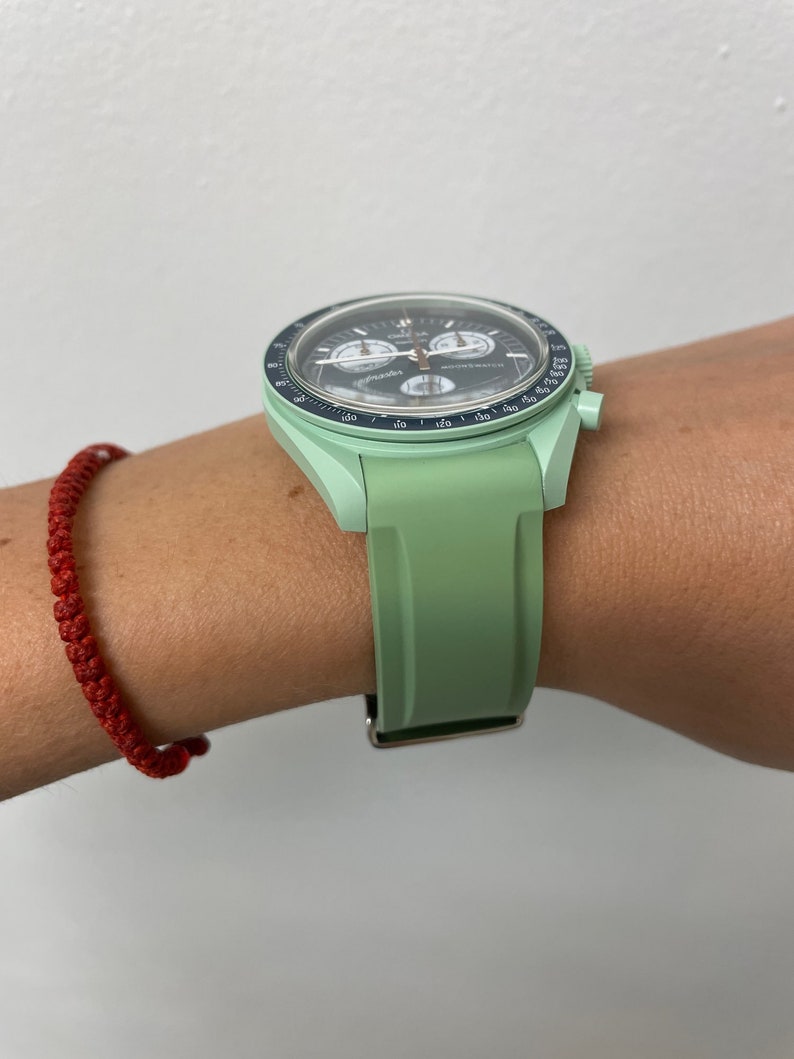 Pu&ograve; includere: Un orologio da polso verde con quadrante nero e lancette argentate. L'orologio ha una funzione cronografo e una scala tachimetrica sulla lunetta. L'orologio &egrave; su un cinturino in gomma verde.