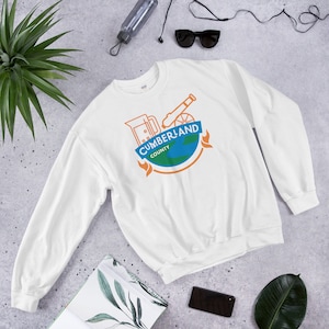 May include: White sweatshirt with a blue and orange graphic design featuring a cannon, a pitcher, and a globe with the text "CUMBERLAND COUNTY".