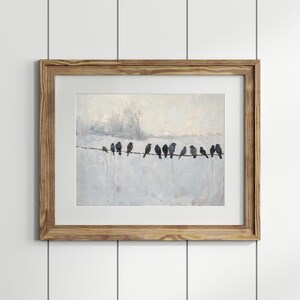 May include: A framed art print featuring a painting of several dark birds perched on a wire against a light, textured background. The artwork is in a wooden frame, creating a rustic aesthetic. The birds are silhouetted.