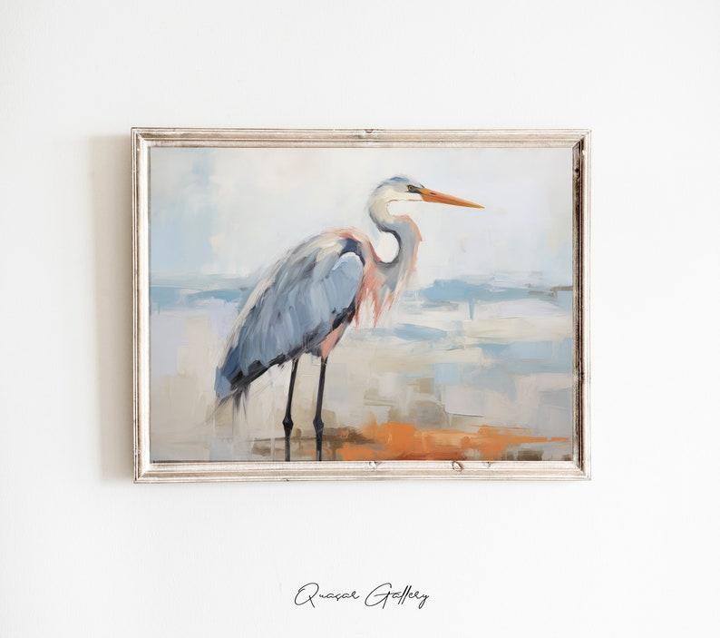 Puede incluir: Una pintura de una garza azul de pie en una playa con un fondo azul claro y blanco. La garza tiene un pico largo y delgado y patas largas. La pintura est&aacute; enmarcada en un marco blanco.