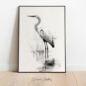 May include: Black and white watercolor painting of a great egret standing in a marsh. The bird is facing to the right and has its head tilted down. The background is a light gray.