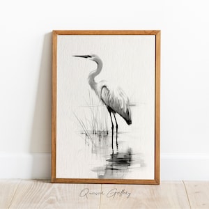 May include: Black and white watercolor painting of a great egret standing in a marsh. The bird is facing to the right and has its head tilted down. The painting is framed in a natural wood frame.