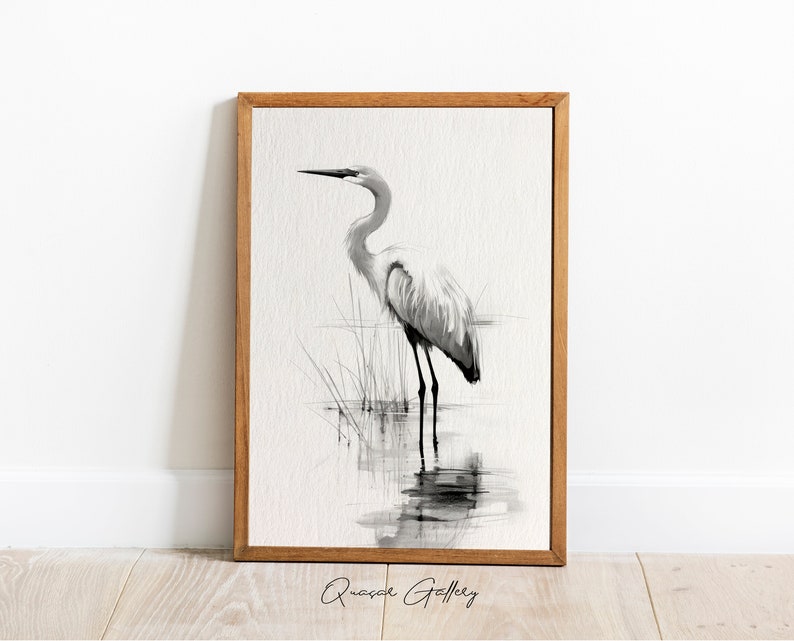 May include: Black and white watercolor painting of a great egret standing in a marsh. The bird is facing to the right and has its head tilted down. The painting is framed in a natural wood frame.