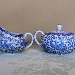 May include: A blue and white porcelain creamer and sugar bowl set with a phoenix design.