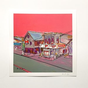 May include: A colourful print depicting a street scene with buildings under a pink sky. The buildings feature signs and awnings, with figures on the pavement. The artwork is rendered in a vibrant, illustrative style.
