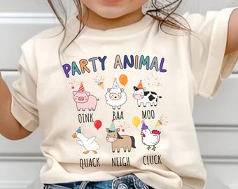 May include: Cream-colored t-shirt with the text "PARTY ANIMAL" in purple, blue, and orange. Below the text are cartoon farm animals with party hats and speech bubbles. The animals include a pig, sheep, cow, duck, horse, and chicken.