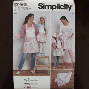 May include: Simplicity sewing pattern number S9565 for a pink and white floral print apron with a ruffled hem. The pattern includes instructions for making a matching apron for a child. The pattern is designed and printed in the USA.