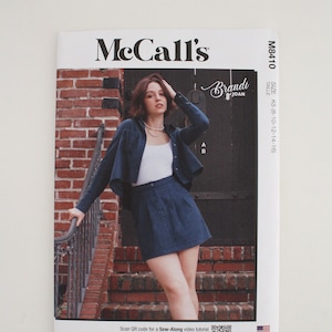 May include: McCall's sewing pattern M8410 for a cropped jacket and skirt. The pattern is for sizes K5 (8-10-12-14-16). The image shows a model wearing the finished garment in a blue denim fabric. The pattern is designed and printed in the USA.