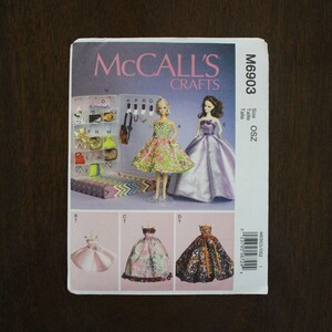May include: A sewing pattern for making four different dresses for dolls. The pattern is from McCall's Crafts and is size OSZ. The pattern includes instructions and diagrams for making the dresses.