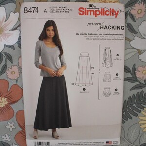 May include: A Simplicity 8474 sewing pattern envelope for sizes XXS-XXL. The front displays a model wearing a grey long-sleeve top and a long dark skirt, with technical line drawings showing four skirt variations including pick-up and ruffle styles.
