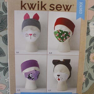 May include: A Kwik Sew K4363 sewing pattern envelope for children's accessories. The cover displays four mannequin heads wearing various fabric headbands and face masks, including cat, peppermint, panda, and dog designs with labeled style variations.