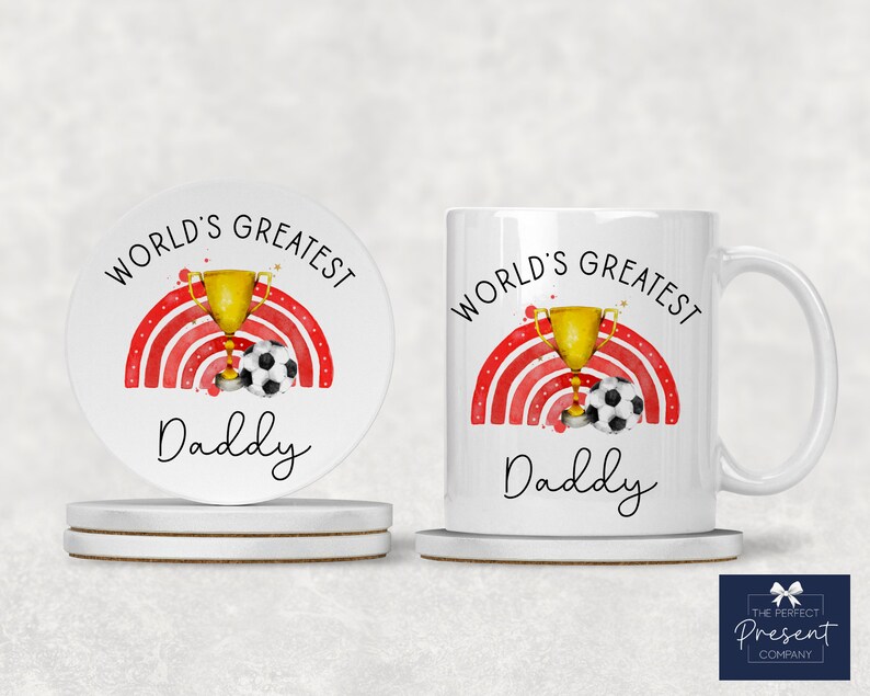 Puede incluir: Taza de cer&aacute;mica blanca con un arco&iacute;ris rojo y blanco, un trofeo dorado y un bal&oacute;n de f&uacute;tbol. El texto "World's Greatest Daddy" est&aacute; impreso en la taza.