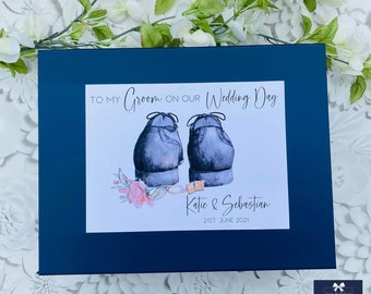 May include: A navy blue gift box with a white card on top. The card has a watercolour illustration of two blue shoes with a floral design and the text "TO MY Groom ON OUR Wedding Day Katie & Sebastian 21ST JUNE 2021".