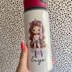 Könnte beinhalten: Weiße Trinkflasche mit rosa und grauem Deckel. Die Flasche zeigt eine Cartoon-Illustration eines Mädchens mit einem Telefon, darunter der Name "Enya". Die Flasche wird vor einem schwarz-weiß gepunkteten Hintergrund gehalten.