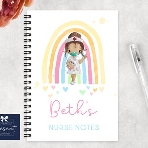 May include: A spiral bound notebook with a colorful rainbow and a cartoon nurse wearing a face mask. The notebook has the text "Beth's Nurse Notes" on the front.