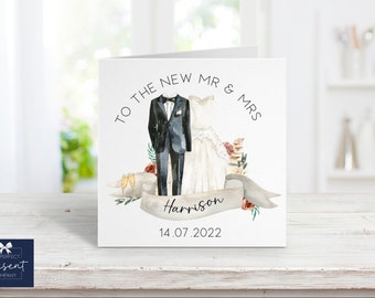 May include: A white card with a watercolor illustration of a bride and groom in wedding attire. The text "To the new Mr. & Mrs. Harrison 14.07.2022" is printed on the card.
