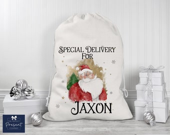 May include: White canvas Santa sack with a watercolor illustration of Santa Claus and the text "Special Delivery For Jaxon".