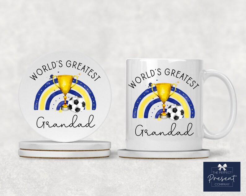 Puede incluir: Conjunto de taza y posavasos de cer&aacute;mica blanca con un arco&iacute;ris azul y amarillo, un trofeo dorado y un bal&oacute;n de f&uacute;tbol. El texto "World's Greatest Grandad" est&aacute; impreso en la taza y el posavasos.