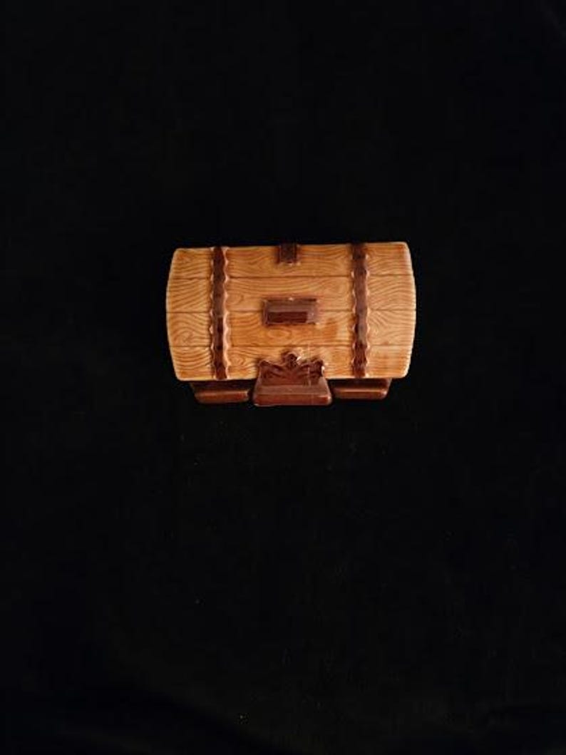 May include: A decorative, barrel-shaped ceramic container with a light brown wood grain finish. Dark brown bands and accents add detail. The container has a small, rectangular door and sits on a dark brown base.